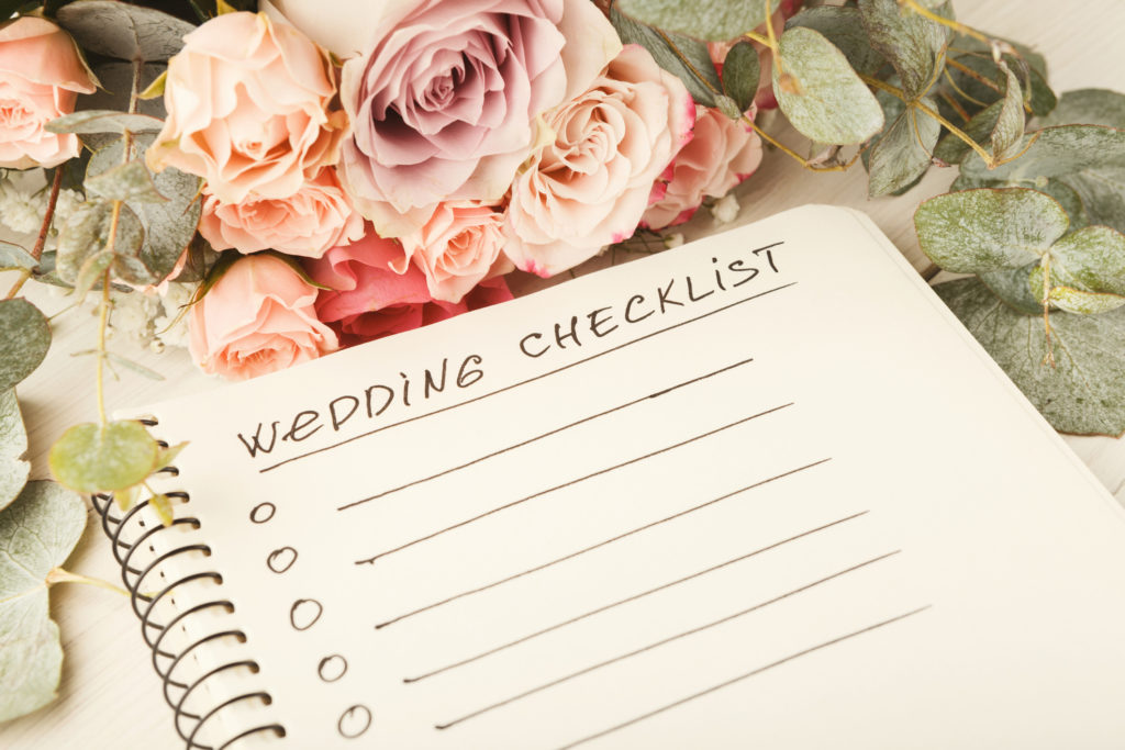 Wedding checklist with copy space and rose bouquet on the white desktop. Marriage planner concept, copy space.