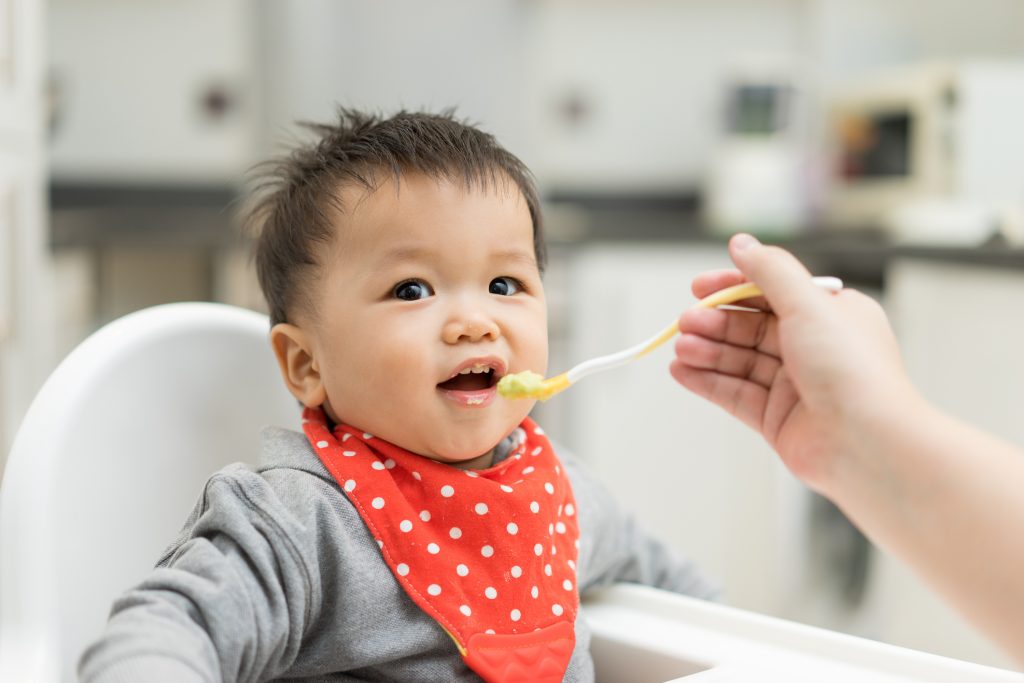 Asian baby boy eating blend food on a high chair