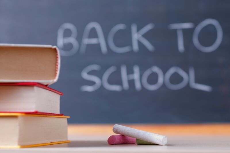 Stack of books in front of a chalkboard that reads "Back to school"