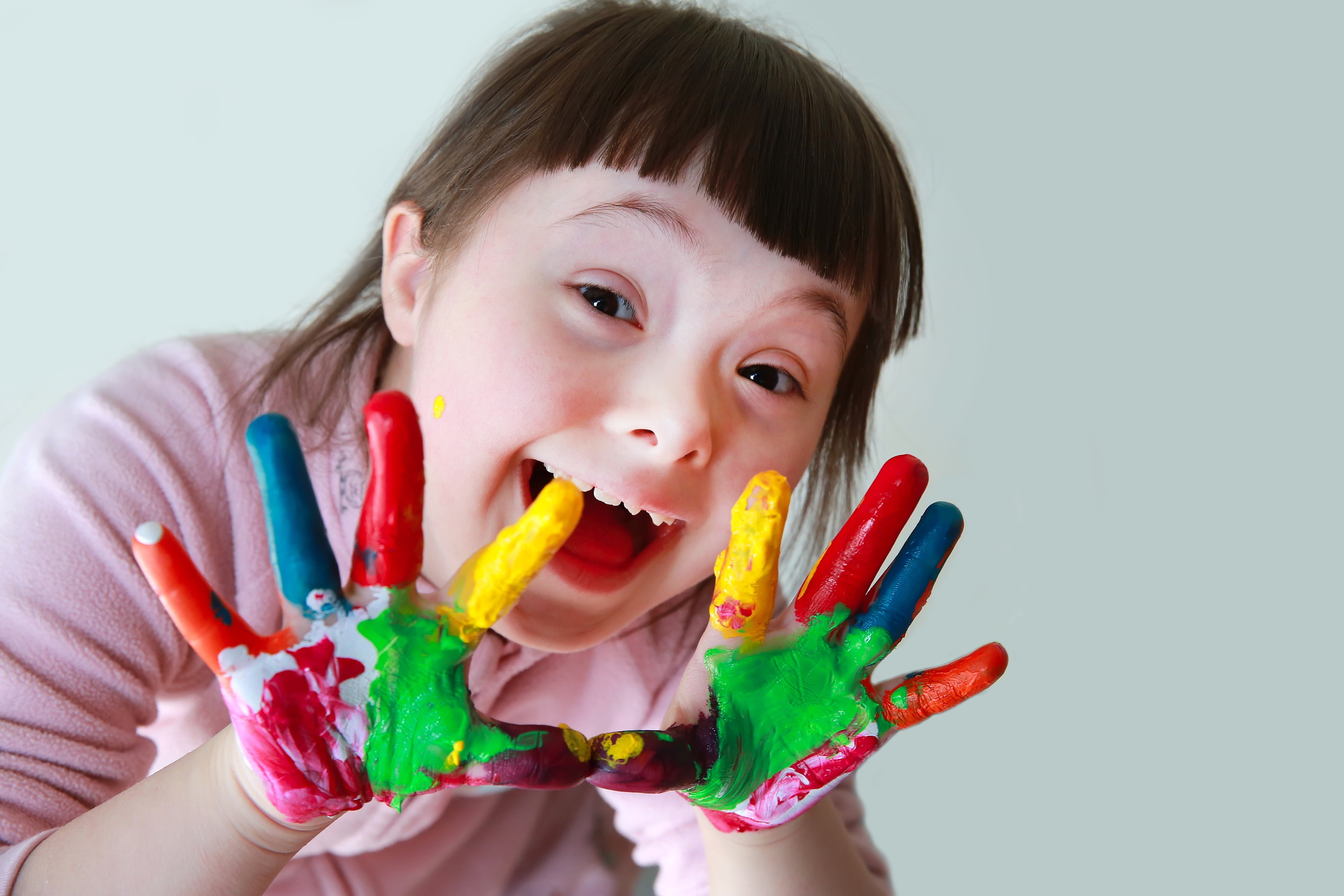Cute little girl with painted hands. Isolated on grey background.