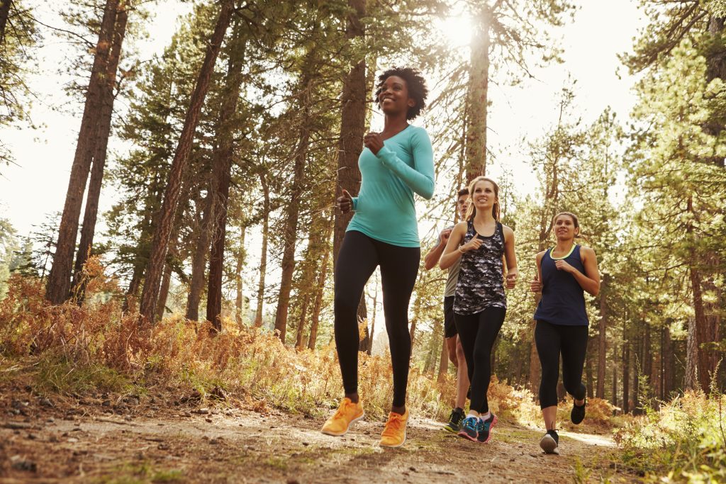 Three women jogging on a trail on a late summer day