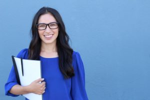 Graduate student holding a notebook smiling at camera