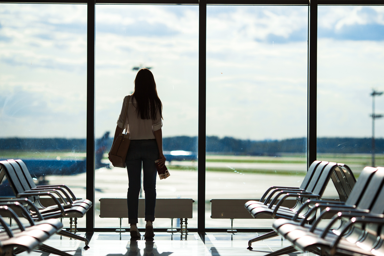 Silhouette of passenger in an airport lounge waiting for flight aircraft