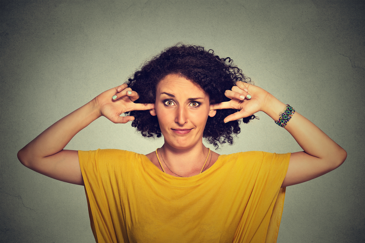 Annoyed woman plugging ears with fingers doesn't want to listen