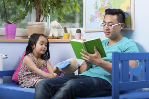 Asian dad reading fairytale to his daughter