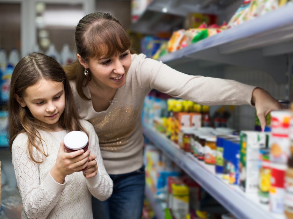 Mom and daughter at the grocery store reading a product ingredient label