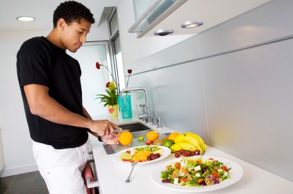 Jeune homme qui prépare une salade de fruits dans sa cuisine