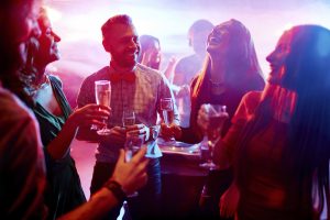 Ecstatic friends with champagne talking at party in night club