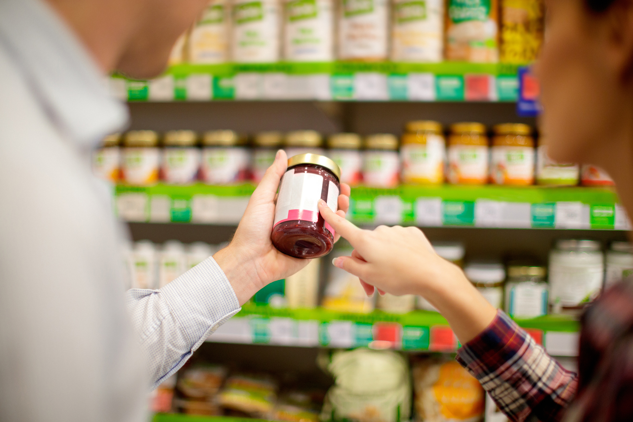 Couple choosing jar of marmalade, reading nutrition label