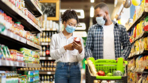 Couple In Shop Buying Groceries Wearing Face Mask