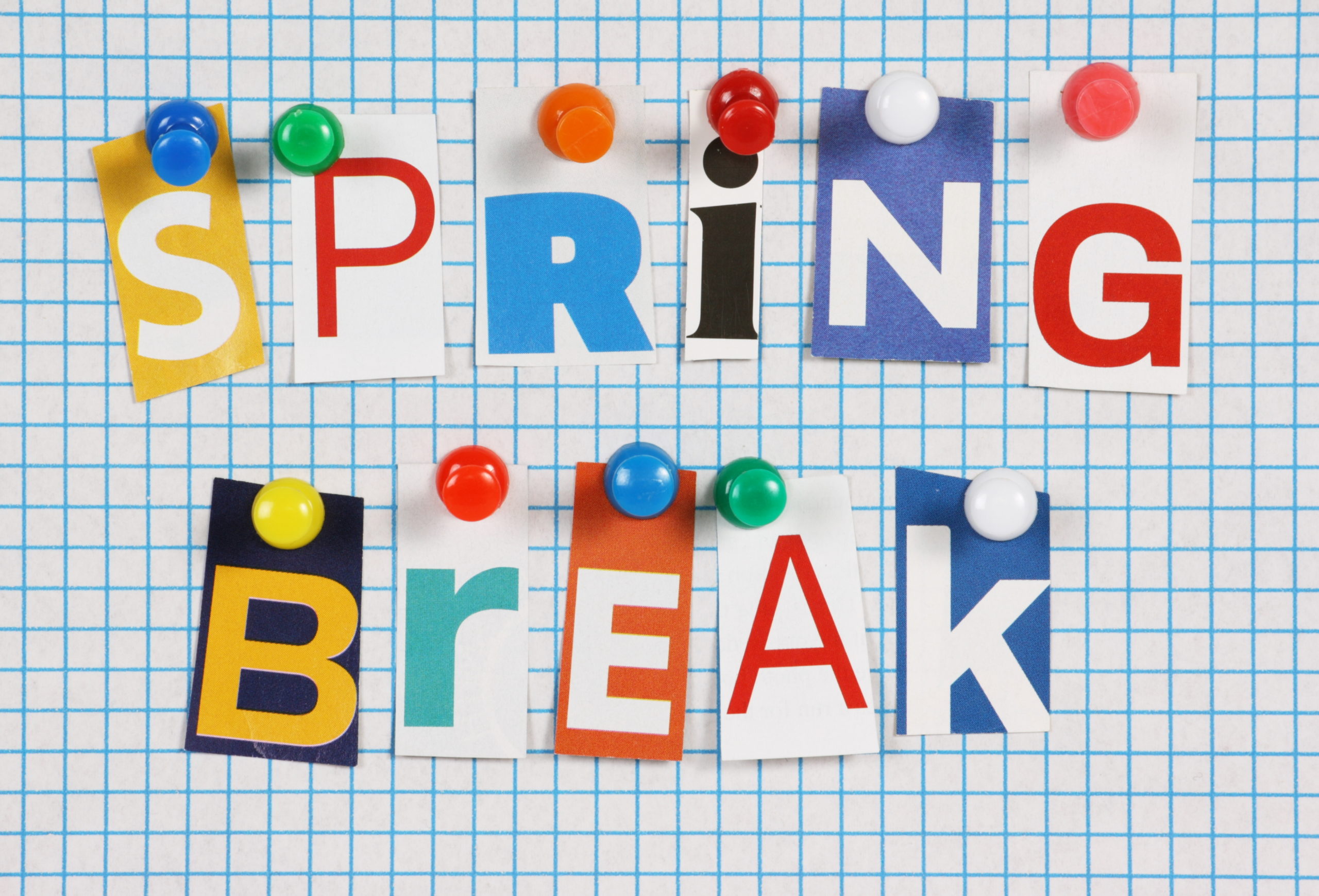 The words Spring Break in cut out magazine letters pinned to a background of blue graph paper