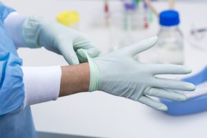 Healthcare professional putting on latex gloves
