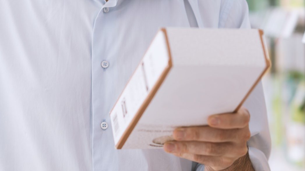 Man doing grocery shopping at the supermarket and reading a food label on a box, shopping and nutrition concept