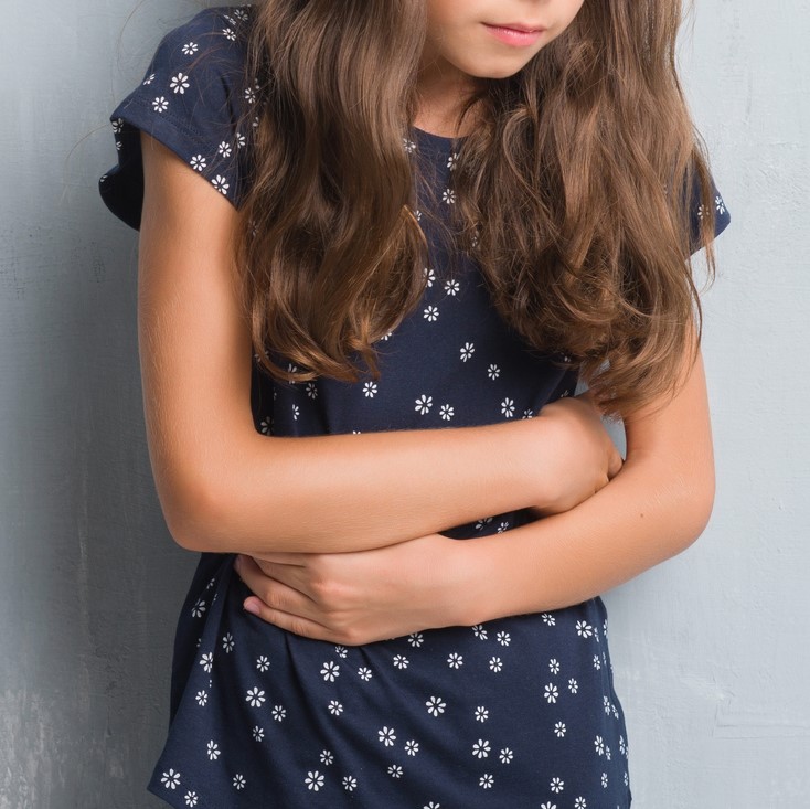 Young girl with hands on stomach because indigestion, painful illness feeling unwell.