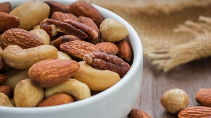 Mixed nuts on wooden table and bowl